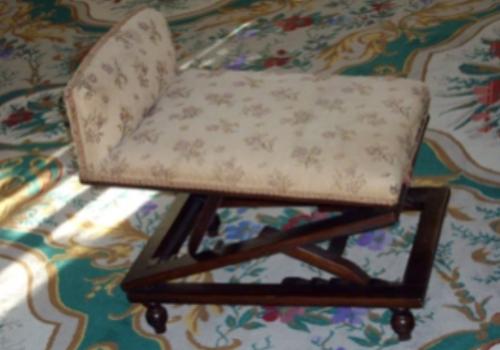 Elegant footstool with floral cushion and wooden frame on detailed carpet.