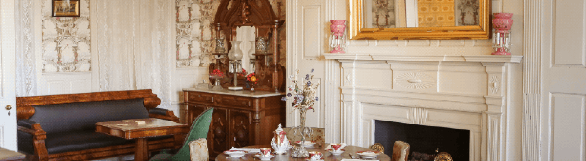 Elegant dining room with vintage furniture, ornate fireplace, and a large mirror.