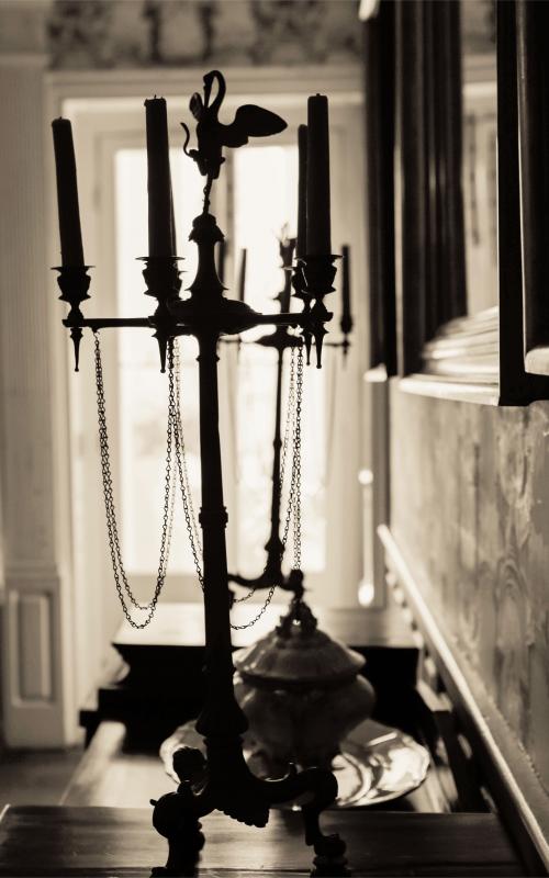 Antique candelabra in dimly lit room with soft light from window.